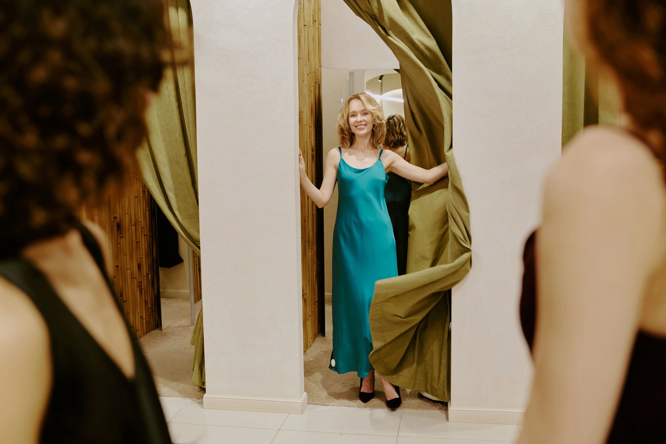 Women admiring a silk dress in a boutique fitting room